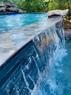 A pool with a waterfall feature, surrounded by a natural landscape. - GEORGE B BOUTIQUE LODGE (Tzaneen)