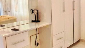 Una camera da letto moderna con un'ampia armadio, una toeletta con specchio e un divano trapuntato.