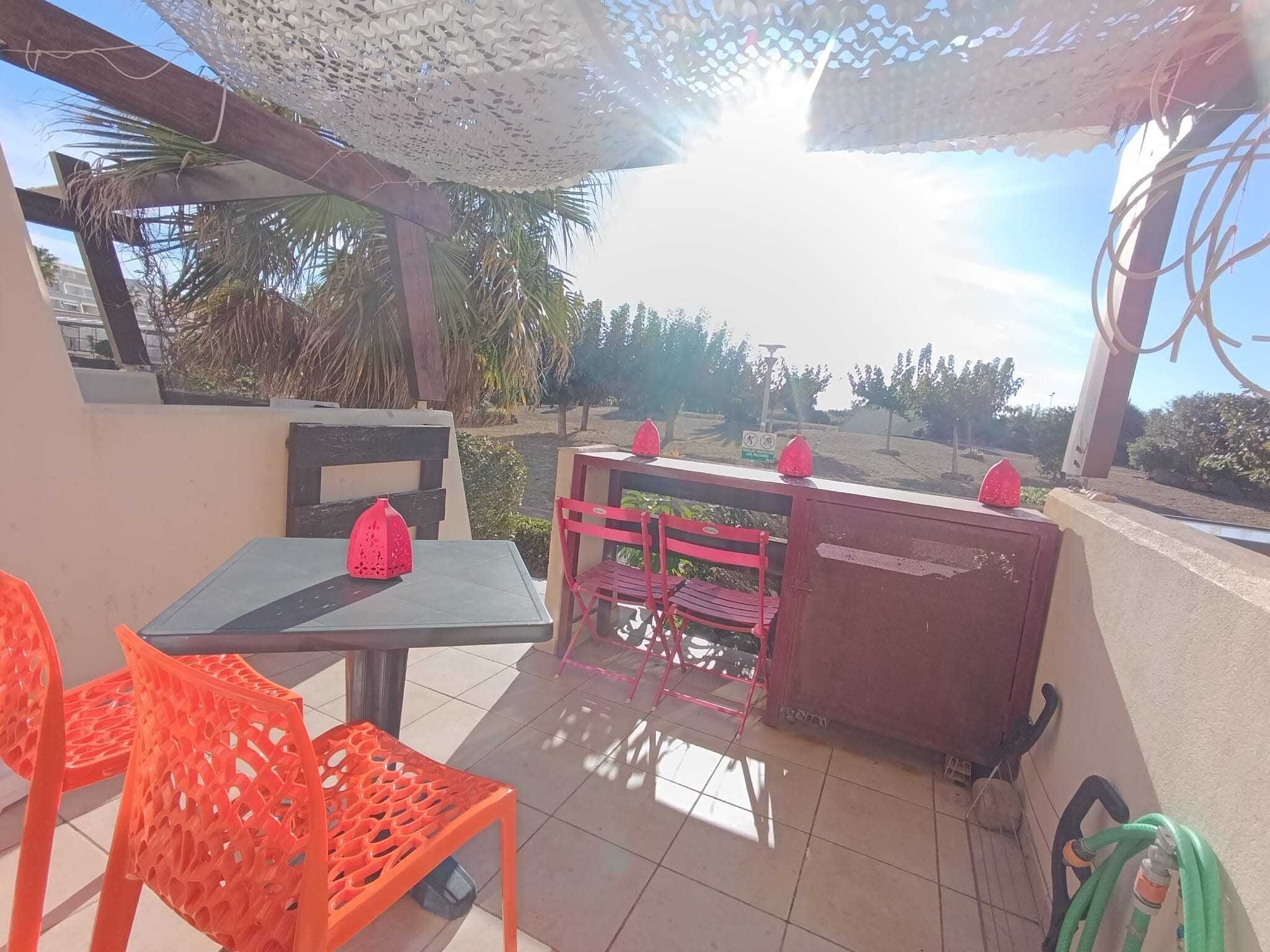 Un espacio de estar al aire libre cubierto con una mesa, sillas y un banco.