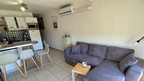 A modern living space with a kitchen, dining area, and a grey sofa. - Naturiste Cap d'Agde Port Nature 804 (Agde)