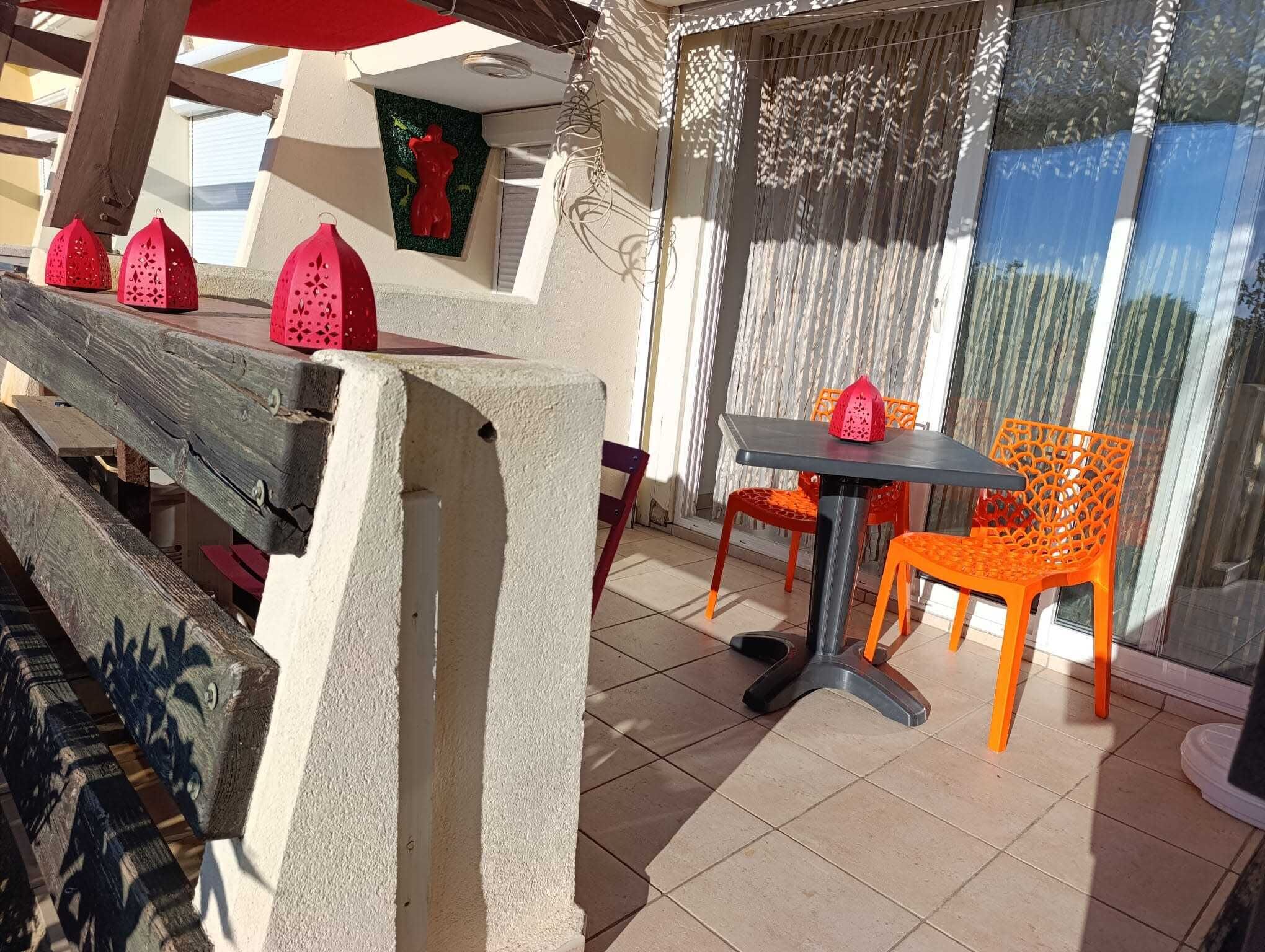 An outdoor patio with a concrete table and chairs, a wooden bench, and a decorative wall with a bear-shaped ornament.