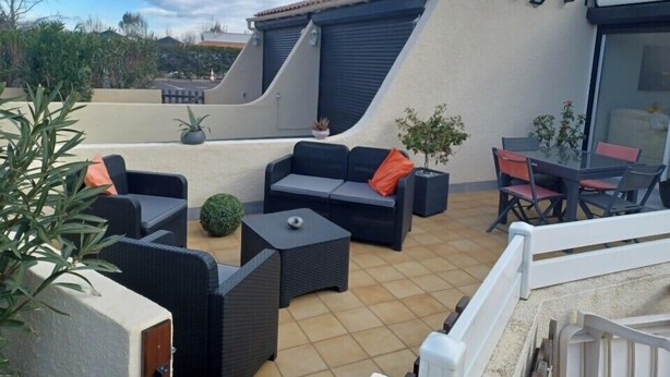 An outdoor patio with a sofa set, a table, and chairs. - Naturiste Cap d'Agde Villa Héliovillage 3 (Agde)