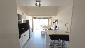 A modern kitchen with a dining area, a sofa, and a table. - Naturiste Cap d'Agde Villa Héliovillage 3 (Agde)