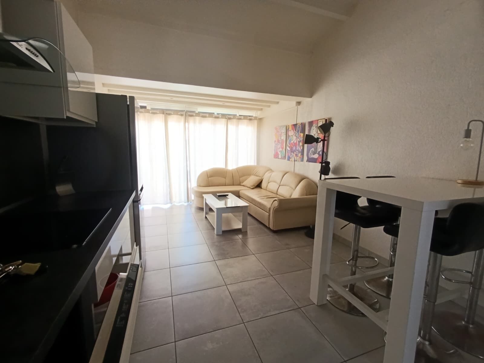 A living room with a sofa, a coffee table, a TV, and a dining area with chairs and a table.