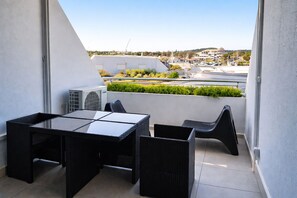 Un balcon avec une table et des chaises, un appareil de climatisation et une vue sur le paysage urbain.