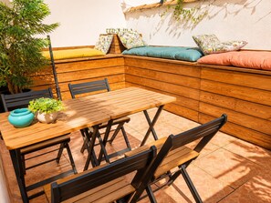 Een houten tafel met stoelen, een bank met kussens en een potplant.