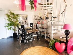 A modern interior with a dining area, staircase, and potted plants.
