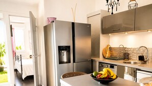 A modern kitchen with stainless steel appliances, a water dispenser, and a bowl of fruit on the counter.