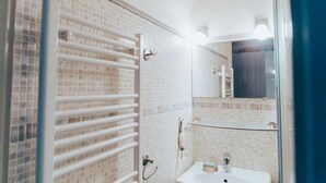 Un bany amb una cabina de dutxa de vidre, un lavabo blanc i un respatller de rajola.