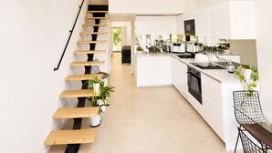 Una cocina moderna con una isla central, un tragaluz y una escalera de madera.