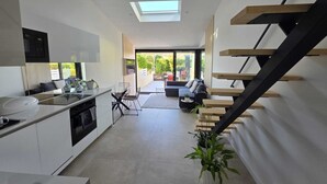 Una cocina moderna con comedor, una escalera y vistas al exterior.