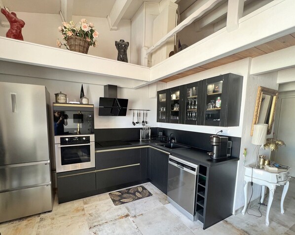 A modern kitchen with a built-in oven, microwave, and dishwasher, a black countertop, and a white backsplash.