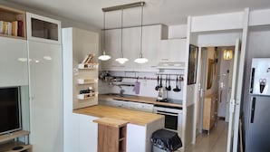 A modern kitchen with white cabinetry, a wooden countertop, and hanging pendant lights.