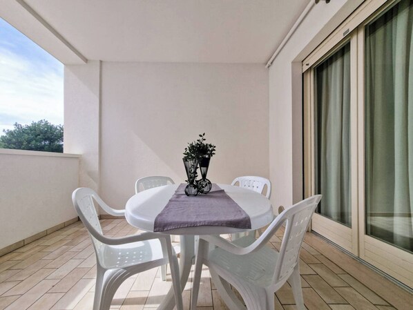Un balcon avec une table et des chaises, une nappe violette et une plante en pot.
