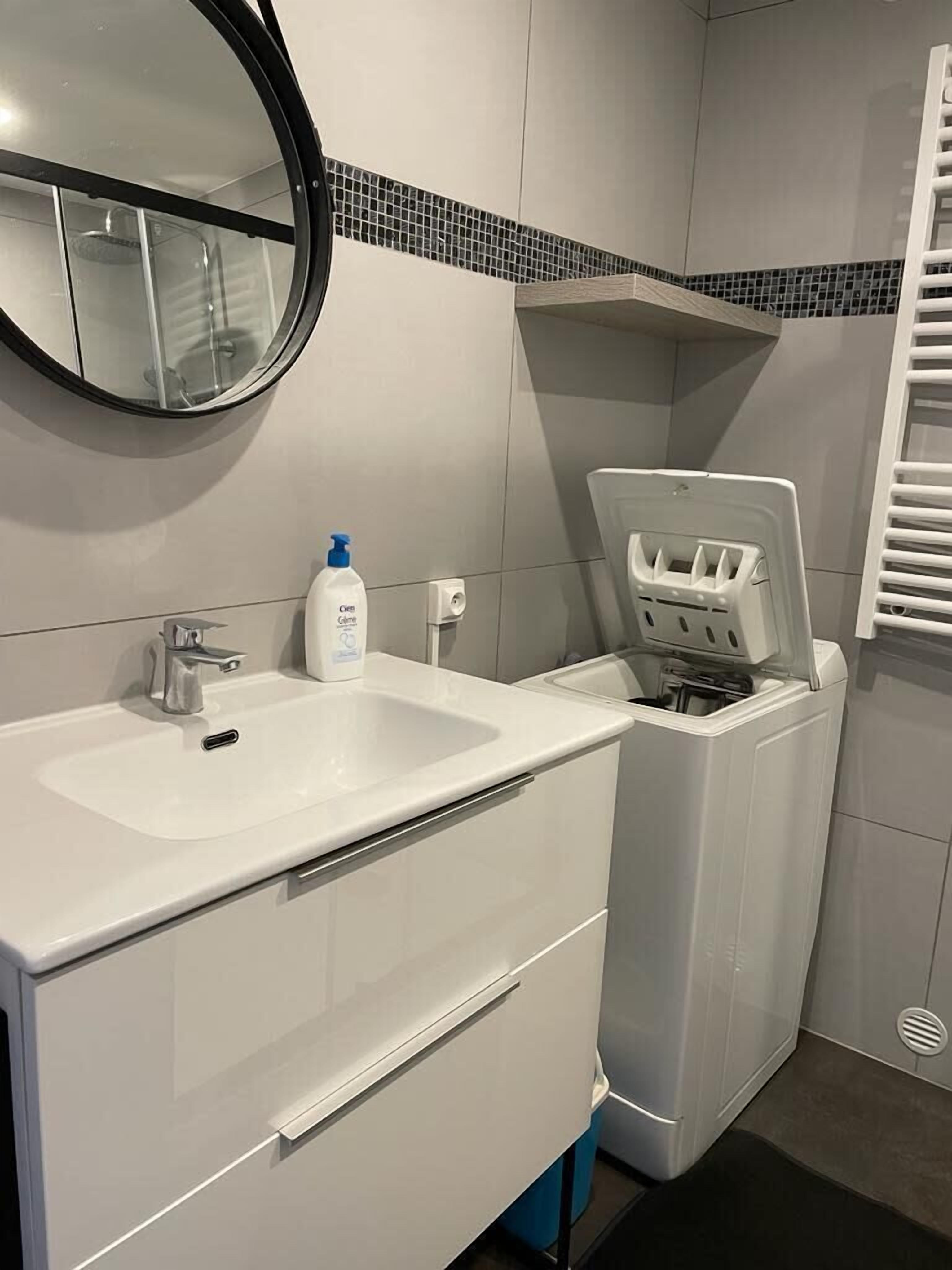 Een moderne badkamer met een witte wastafel, een spiegel en een wit toilet met deksel.