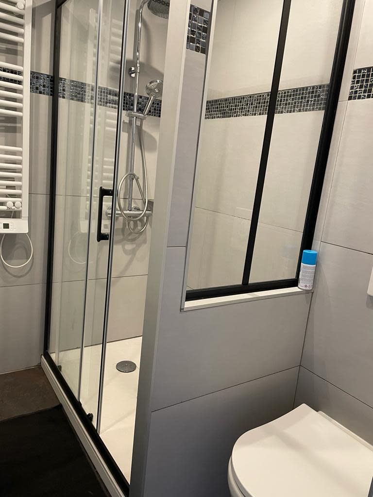 A modern bathroom with a glass-enclosed shower, a toilet, and a towel rack.