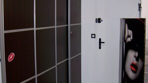 Een kamer met een schuifdeur, een witte deur en een houten vloer.