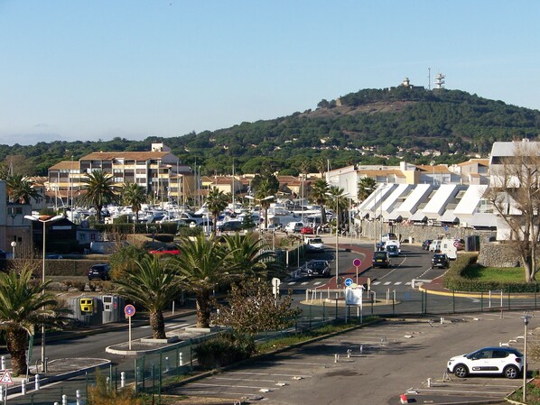 Un pueblo costero con un puerto deportivo, coches aparcados y edificios de techos planos.