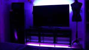 Een kamer met een flatscreen televisie op een standaard, een dressoir en een etalagepop.