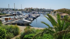 A marina with numerous boats docked along a narrow waterway, surrounded by buildings and greenery.