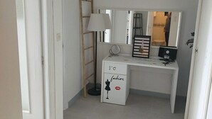 A small, white room with a desk, a mirror, a lamp, and a ladder. - Naturiste Cap d'Agde Héliopolis F 71 (Agde)