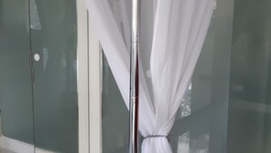 A modern room with a glass partition, a round dark-colored table, and a white curtain.