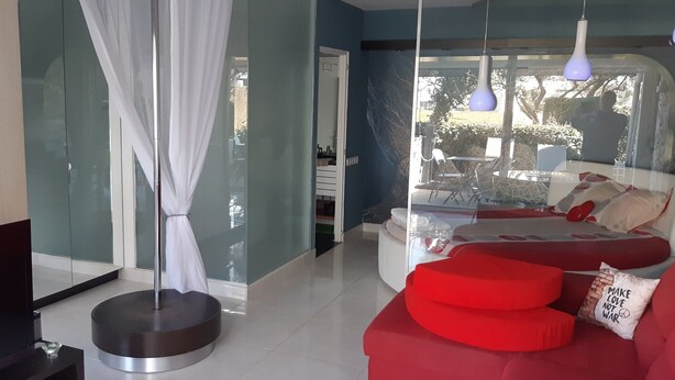 A modern living room with a red sofa, a glass partition, and a white curtain.