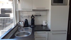 A compact kitchen with a sink, a kettle, a coffee maker, and a microwave.