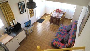 Een compacte woonruimte met een kitchenette, een eethoek, een bank en een trap.