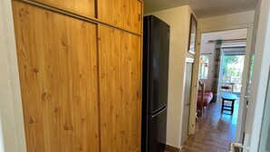 Eine Küche mit Holzausstattung, einem schwarzen Kühlschrank und einem Fliesenboden.