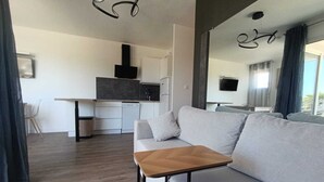 Un moderno salón con un sofá, una mesita de madera y una cocina al fondo.