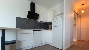 Cocina moderna con armarios blancos, extractor de aire negro y refrigerador blanco.