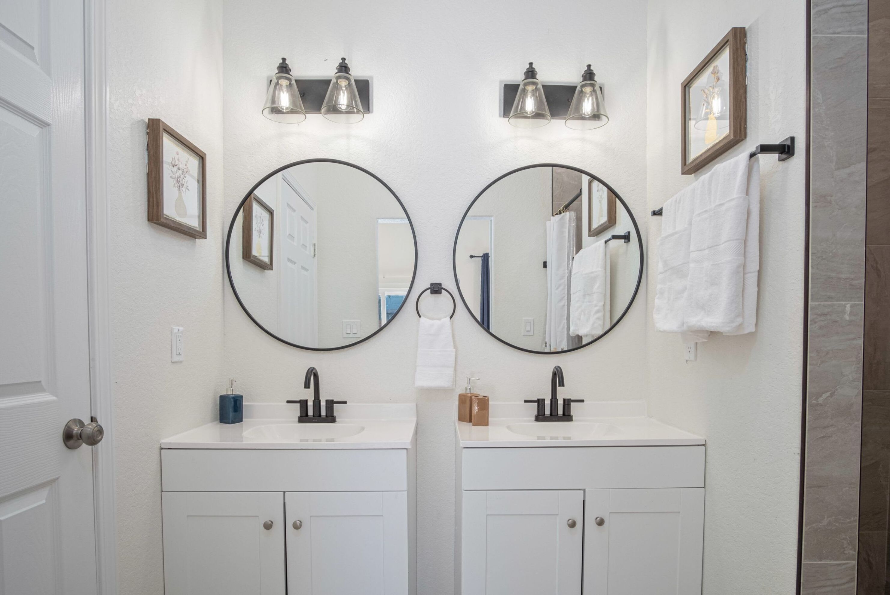 A bathroom with two sinks, a mirror, and a towel rack.