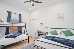 A dorm-style room with bunk beds, a desk, and a chair.