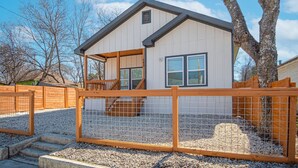 A single-story house with a porch, a wooden fence, and a gravel driveway. - Feel Chill and Enjoy 4BR 3BA Near Fun Riverwalk (San Antonio)