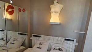 A bedroom with a bed, a mirror, and a mannequin. - Naturiste Cap d'Agde Héliopolis F 61 (Agde)