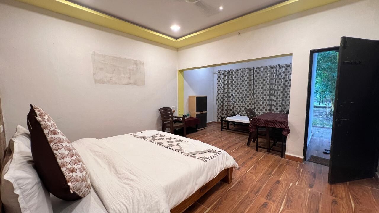 A bedroom with a bed, a desk, and a chair. There is a door leading to a balcony.
