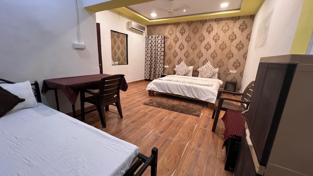A hotel room with two beds, a table, and a TV.