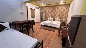 A hotel room with two beds, a table, and a TV.