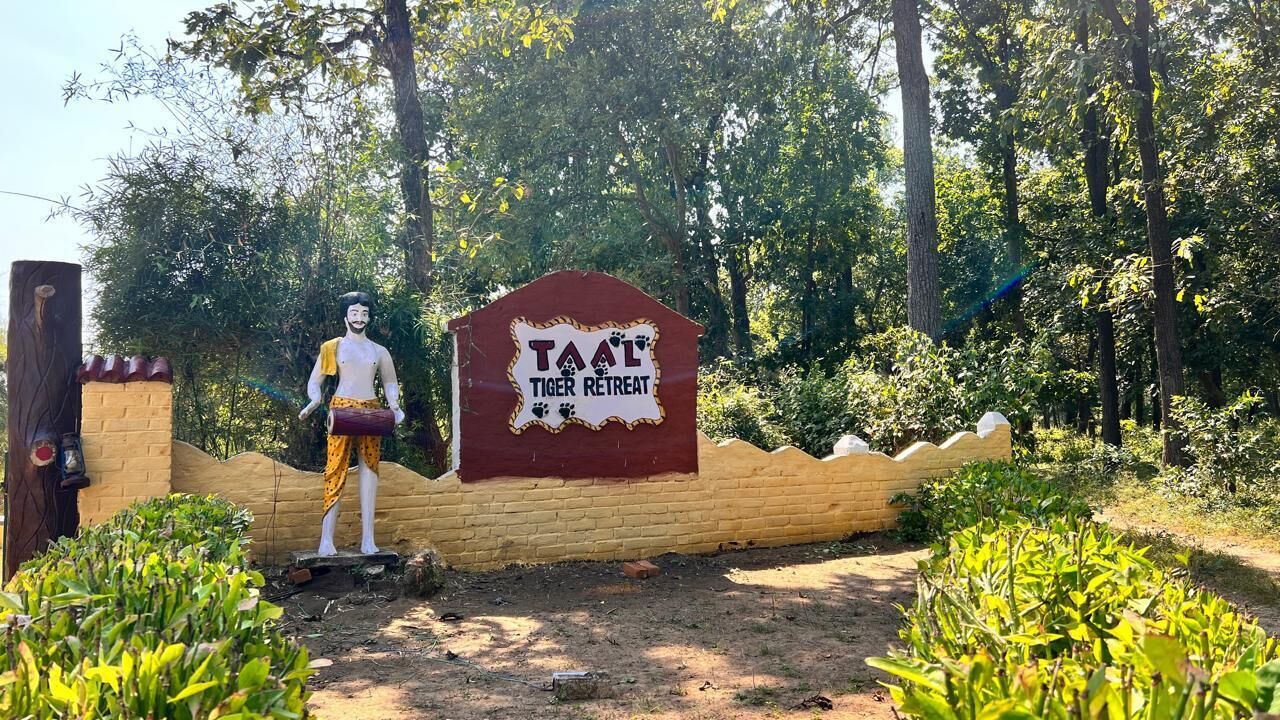 A sign for 'Taal Tiger Retreat' with a statue of a man in traditional attire.