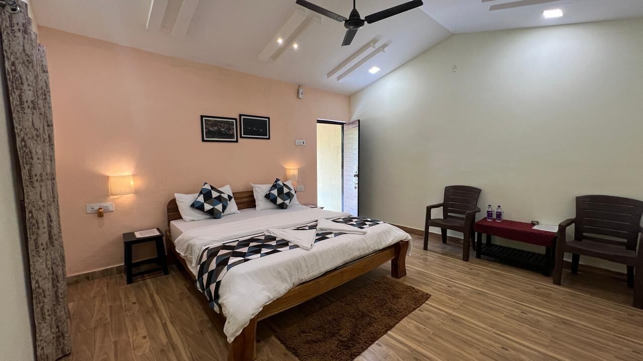 A bedroom with a bed, bedside tables, a ceiling fan, and a small table with chairs.