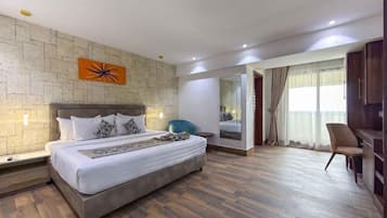 Een moderne hotelkamer met een groot bed, een spiegel, een zithoek en uitzicht op het omliggende landschap.