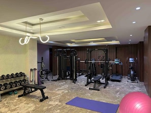 A gym with various exercise equipment, including dumbbells, a bench, and cardio machines. - Blue Orange Hotel and Towers (Lagos)