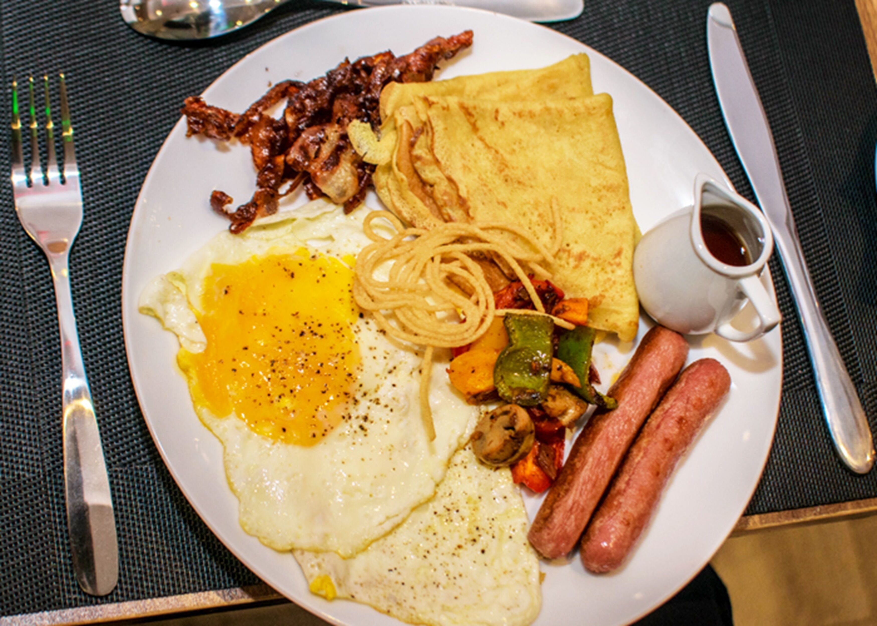 A plate of breakfast food including eggs, sausages, and vegetables.
