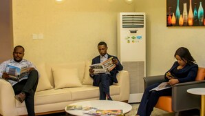 Ein stilvoller Lounge-Bereich mit einem beigen Sofa, einem runden Couchtisch und einer Wand-Klimaanlage.