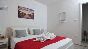 A hotel room with a bed, a bedside table, a nightstand, a mirror, and a painting on the wall. - Charming 2-bedroom apartment with WiFi, AC in enchanting Dubrovnik (Dubrovnik)