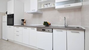 A modern kitchen with white cabinetry, a built-in oven, a dishwasher, and a stainless steel sink. - Charming 2-bedroom apartment with WiFi, AC in enchanting Dubrovnik (Dubrovnik)