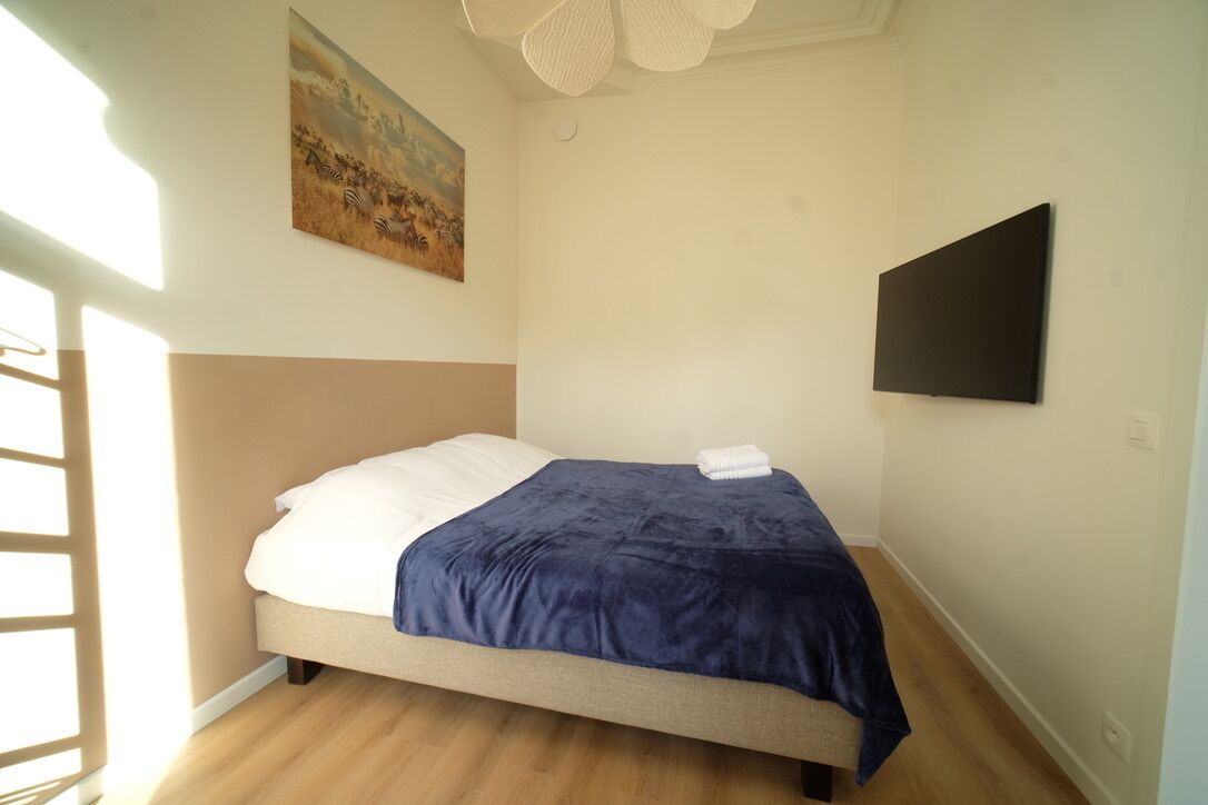 Une chambre à coucher avec un lit, un tableau au mur et un téléviseur à écran plat.