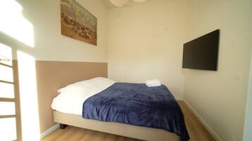 Une chambre à coucher avec un lit, un tableau au mur et un téléviseur à écran plat.
