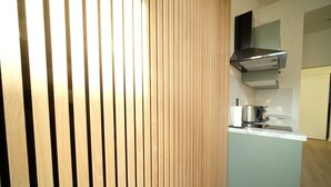A kitchen with a wooden panel wall, a stainless steel range hood, and a countertop with a coffee maker. - Smart appart - downtown (Brussels)